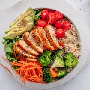 Grilled chicken, rice, carrots, spinach, broccoli, tomatoes, and avocado.