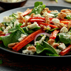 Roasted carrot salad with feta cheese, walnut and spinach. healthy food.